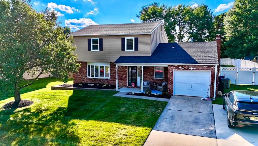 Residential property during the daylight with a beautiful green lawn with a tree planted and a SUV in the driveway